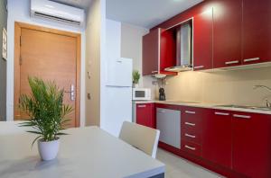 a kitchen with red cabinets and a table with a plant at Apolo Suites Rentalmar in Salou