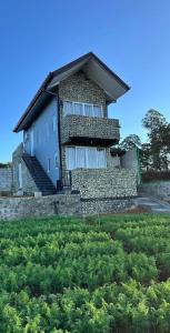 a house with a stone wall and a yard with bushes at SSR Wasana in Sita Eliya +6 photos