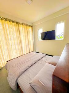 two beds in a bedroom with two windows at SSR Wasana in Sita Eliya