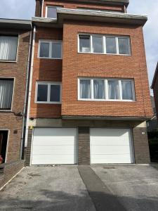 a brick house with two white garage doors at Brussels Expo & Atomium Prestige Suites in Grimbergen