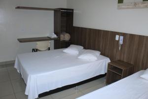 a bedroom with two beds with white sheets at Via Hotel in Monte Alegre de Minas