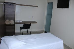 a bedroom with a bed and a desk with a chair at Via Hotel in Monte Alegre de Minas