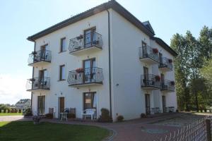 a large white building with balconies and a yard at Pensjonat nad Stawem in Sarbinowo