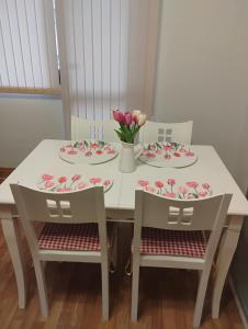 a white table with two chairs and plates and flowers at STADIUM 1 Apartments Sandanski in Sandanski