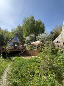 a small cabin with a deck and an umbrella at Eywa House in Kamenskoye Plato
