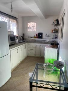 a kitchen with white cabinets and a glass table at Comme chez moi in El Harhoura