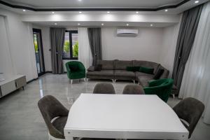 a living room with a white table and green chairs at Villamona Dalaman in Bezkesen
