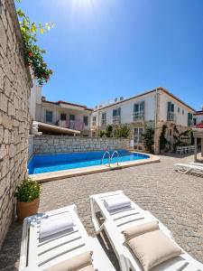 a pool with white lounge chairs next to a building at F&G Alaçatı in Alaçatı