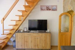 a television on a wooden cabinet under a staircase at Árnyas Tölgy in Kismaros