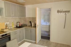 a kitchen with white cabinets and a sink and a refrigerator at Árnyas Tölgy in Kismaros