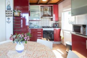 a kitchen with red cabinets and a table with a vase of flowers at AG Casa Camariñas, con jardín y vistas al mar in Camariñas +15 photos