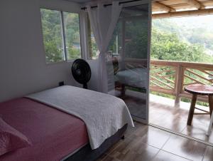 a bedroom with a bed and a balcony at La Cabañita VIP Amanecer in Minca