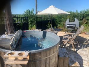 a hot tub sitting on a deck with an umbrella at Stable End in Liskeard +19 photos