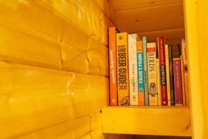 a row of books on a wooden book shelf at The Chestnuts Pod with private garden. in Eccles
