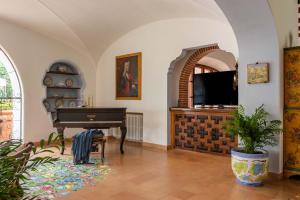 a living room with a piano and a television at Villa Le Pagine Bianche in Lacco Ameno