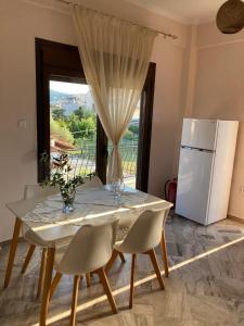 a white table with chairs and a white refrigerator at Villa Eleon 1 in Nea Vrasna