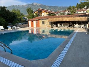 a large swimming pool with a building and mountains in the background at Ünlü Otel in Fethiye