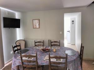 a dining room with a table and chairs and a television at Gîte du Domaine du Moulin de la Roque in Castels