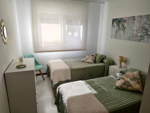 a small room with two beds and a window at Arenales Azules in Baiona