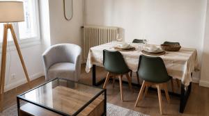 a dining room with a table with green chairs and a glass table at L'Écrin Bois & Lin in Nevers