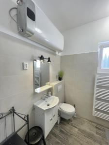 a white bathroom with a toilet and a sink at Víkend Apartmanok in Révfülöp
