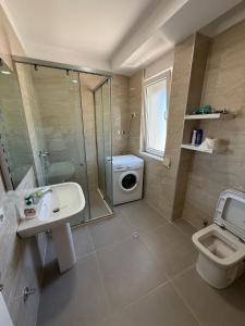 a bathroom with a shower sink and a washing machine at Leonard's Shengjin Apartments in Lezhë +48 photos