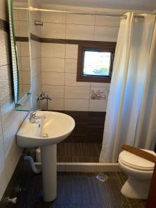 a bathroom with a sink and a toilet and a window at Villa Eleon 2 in Nea Vrasna