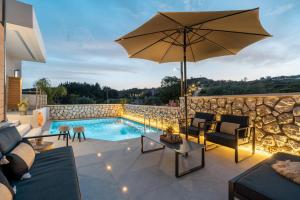 a patio with an umbrella and a swimming pool at Eldorado Luxury Villa in Afantou