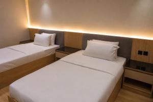 two beds in a hotel room with white pillows at Abha Elite Suites ابها ايليت سويتس in Abha