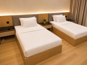 two beds in a hotel room with white sheets at Abha Elite Suites ابها ايليت سويتس in Abha