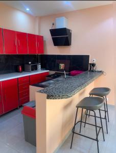 a kitchen with red cabinets and a counter with stools at Immeuble Racine in Ngaparou