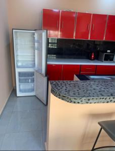 a kitchen with red cabinets and an open refrigerator at Immeuble Racine in Ngaparou +5 photos