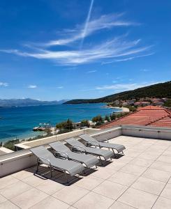 a row of chaise lounge chairs on a patio overlooking the ocean at Slatine Residence apartament No2 in Slatine