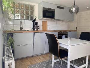 a kitchen with white cabinets and a white table and chairs at Centralt Semesterboende in Halmstad