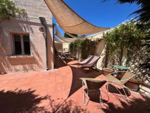 a patio with chairs and tables on a brick patio at Bastide le Petit Clos - les 2 Gîtes in Perpignan