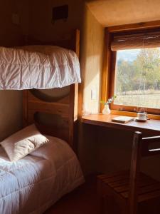 a bedroom with a bunk bed and a desk with a window at Posada La Tregua in El Bolsón