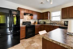 a kitchen with wooden cabinets and a black refrigerator at Guest House Haven with Gazebo in Riverdale