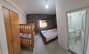 a bedroom with a bunk bed and a bathroom at Sylbica Guesthouse in Tropojë
