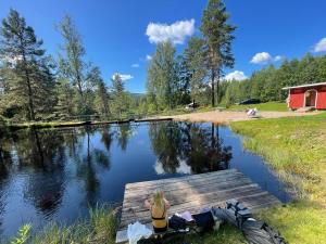 a woman sitting on a dock over a lake at Stuga i Branäs Byn in Sysslebäck