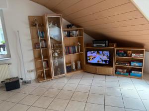 a living room with a tv and book shelves at Ferienwohnung Rosengarten in Osburg