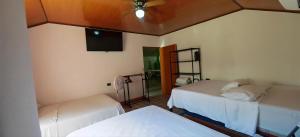 a room with two beds and a flat screen tv at Rancho Amigos Columbias Caldera in Esparza