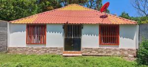 a small house with an orange roof and two windows at Rancho Amigos Columbias Caldera in Esparza