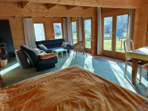 a living room with a couch and chairs and windows at Haus im Garten in Grebenau