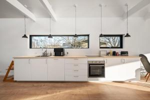 a kitchen with white cabinets and black appliances at Sortehus - 100 steps from the finest beach in Vallebo +22 photos