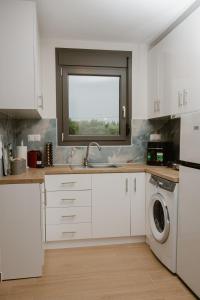 a white kitchen with a sink and a window at Nerina House in Paralia Katerinis