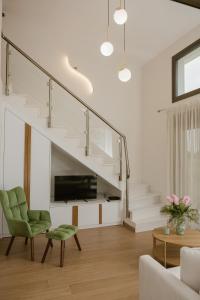 a living room with a staircase and a green chair at Nerina House in Paralia Katerinis