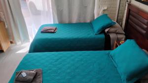 two beds in a room with blue sheets at Hostal Donde Rita in Vicuña
