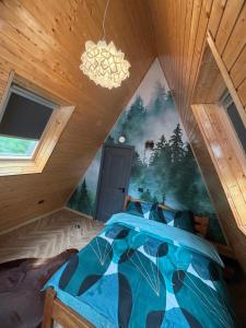 a bedroom with a blue bed with a painting on the wall at Cabana Stefan cel Mare in Căpăţîneni-Ungureni