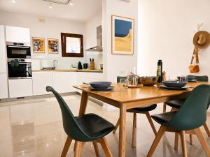 a kitchen with a wooden table and green chairs at Harba - An Escape at Fort Chambray in Għajnsielem