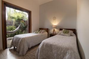 two beds in a room with a window at Casa Viva Itamambuca in Ubatuba